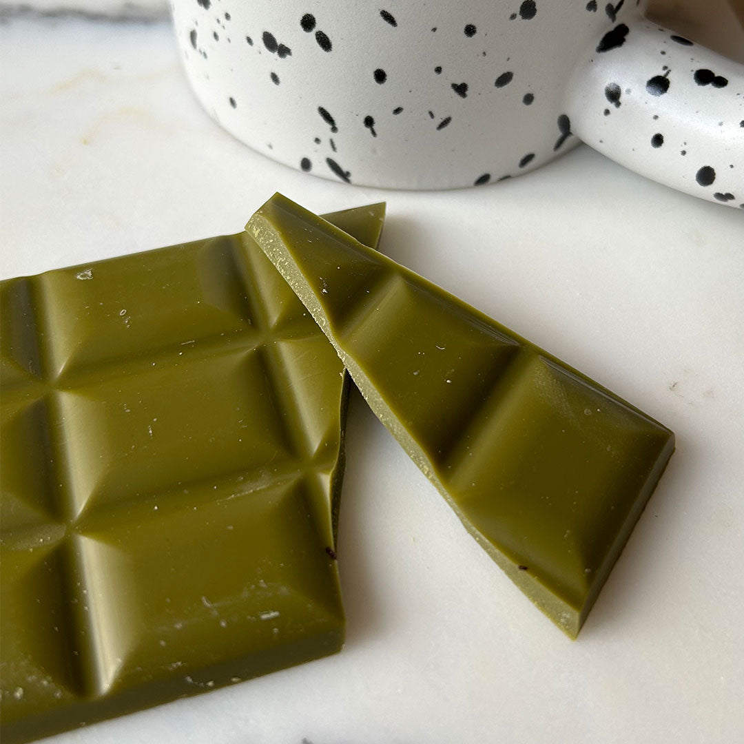 Organic Matcha Chocolate by Health Bar gebrochen vor Tasse